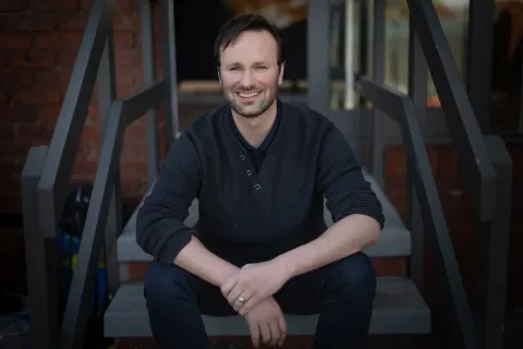 Chris Varney sitting on steps facing the camera