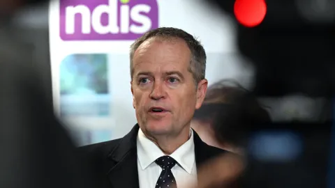 Bill Shorten in  front of NDIS logo