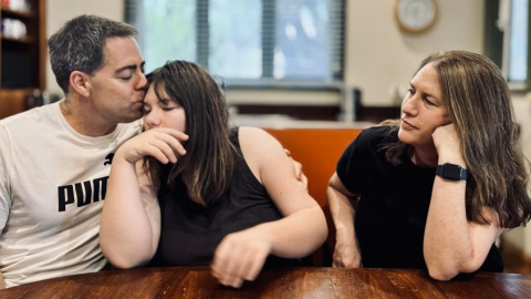 father kissing daughter's forehead - mother watching