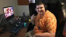 Jesse with headphones & laptop computer looking at camera, hand doing V for victory