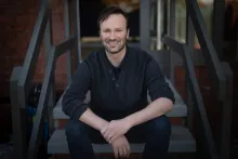 Chris Varney sitting on steps facing the camera