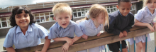 children leaning on a schoolyard fence